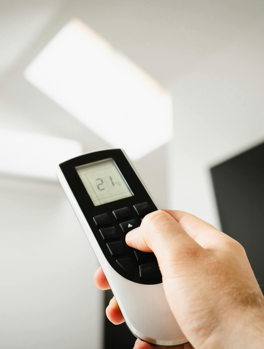 Person using a remote to change the temperature on an indoor unit.